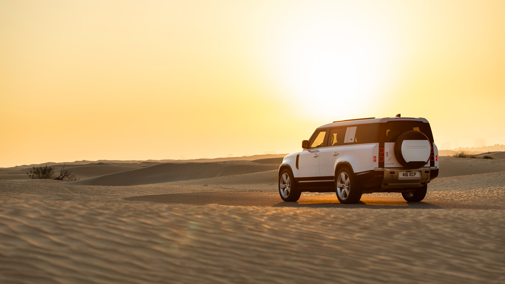 A 2023 Land Rover Defender 130 amidst the sand dunes of Dubai.